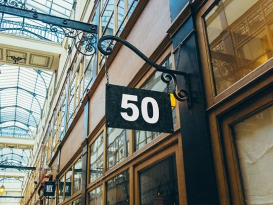 Building facade with a sign displaying the number 50 in an indoor setting with glass ceiling.