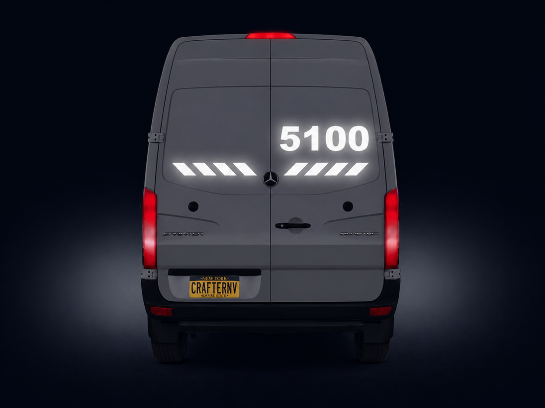 Back view of a gray van with visible Mercedes logo on a dark background